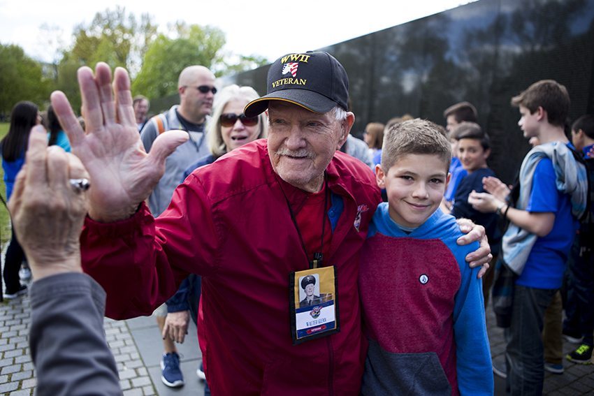 Veterans arrive at Vietnam War Memorial, greeted by applauding high school students. 