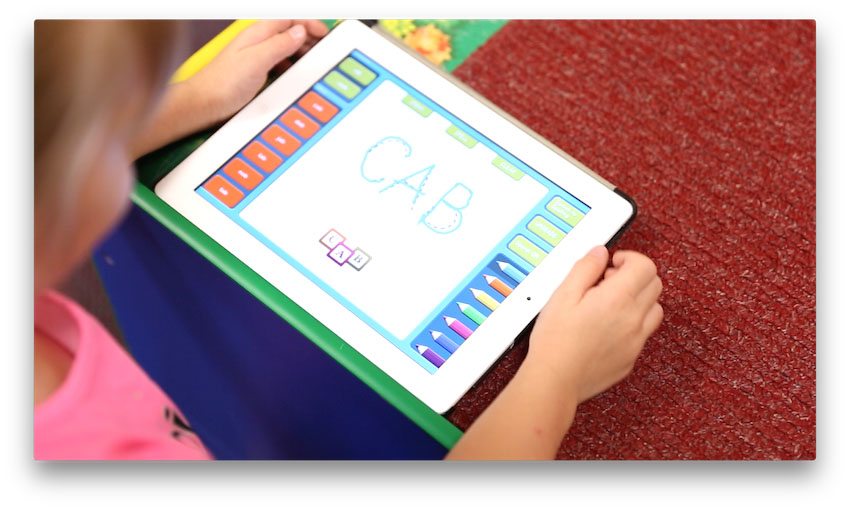 Kindergarten students use iPads to help them spell.