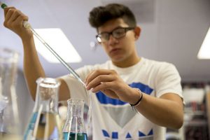 Javier Carrillo, '18, uses a pipette to pour liquid into a dialysis bag to represent a cell  