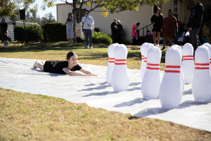 Junior Addyson Adler, hurls herself down the lane as a human bowling ball during the lunch princess pageant, Oct. 26.