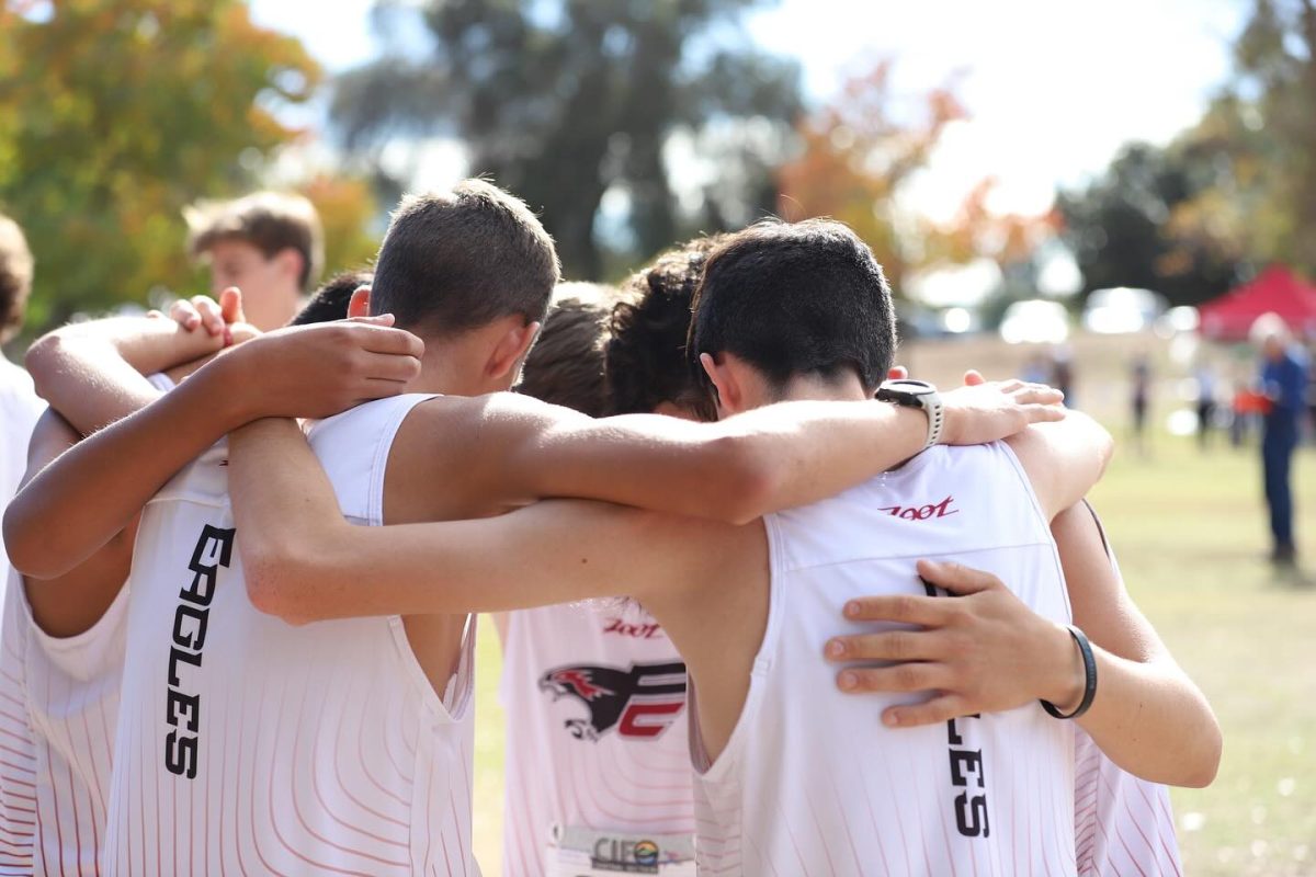 The Cross Country Boys Team prays minutes before the start of their race. In the picture, lead runners, Freshman Blake Bay, and Junior Jacob Pimentels backs are closest to the camera.