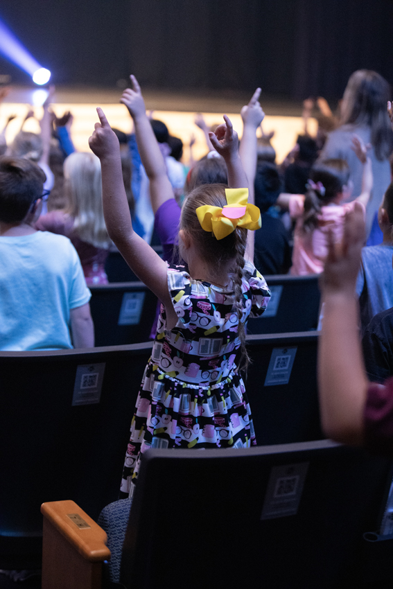Students participate in worship by doing their hand motions, May 2. 