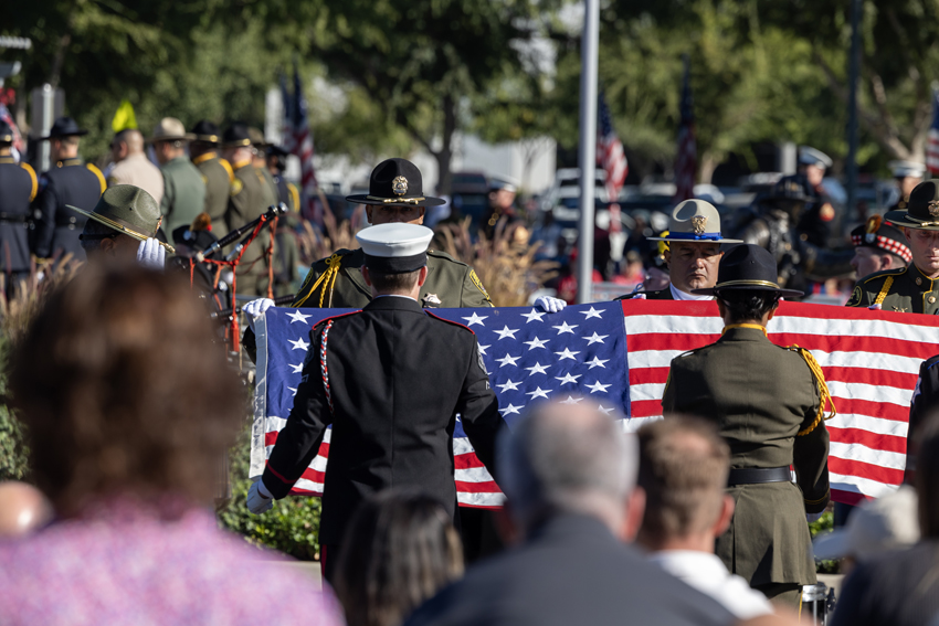 The American Flag is folded 13 times to represent the original 13 colonies, and is presented to guest speaker George Martin.