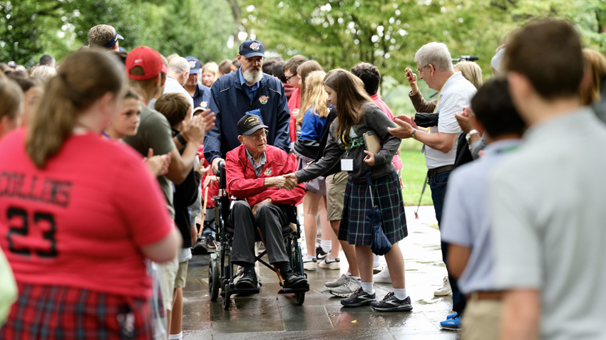 School children gathered to honor and shake hands with veterans as they left Arlington. 