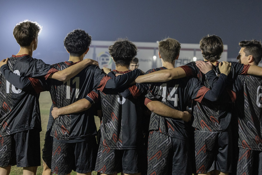 FC boys soccer team huddling while being coached mid game.