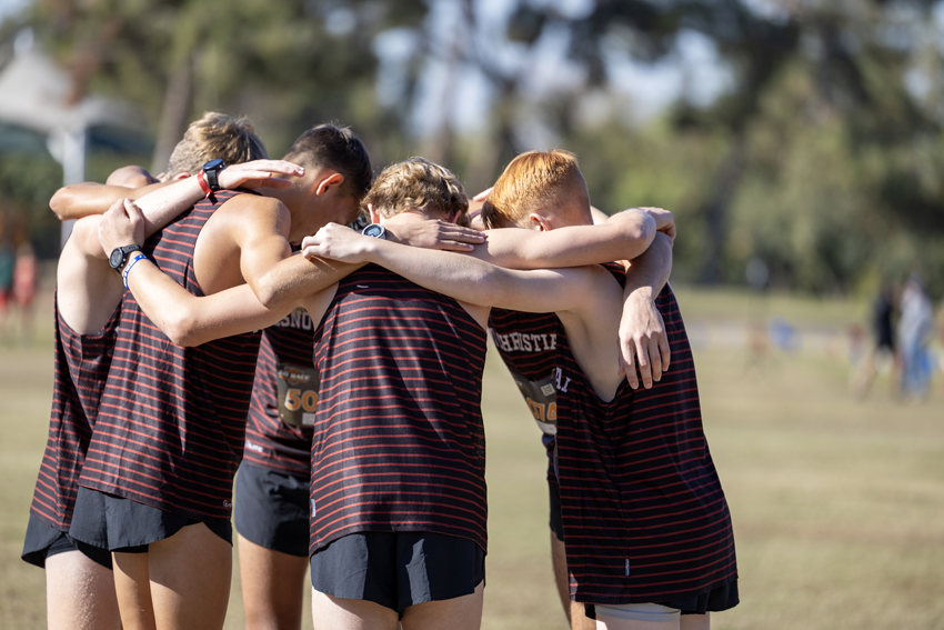 The boys cross country team huddles up and prays before competing in the race.