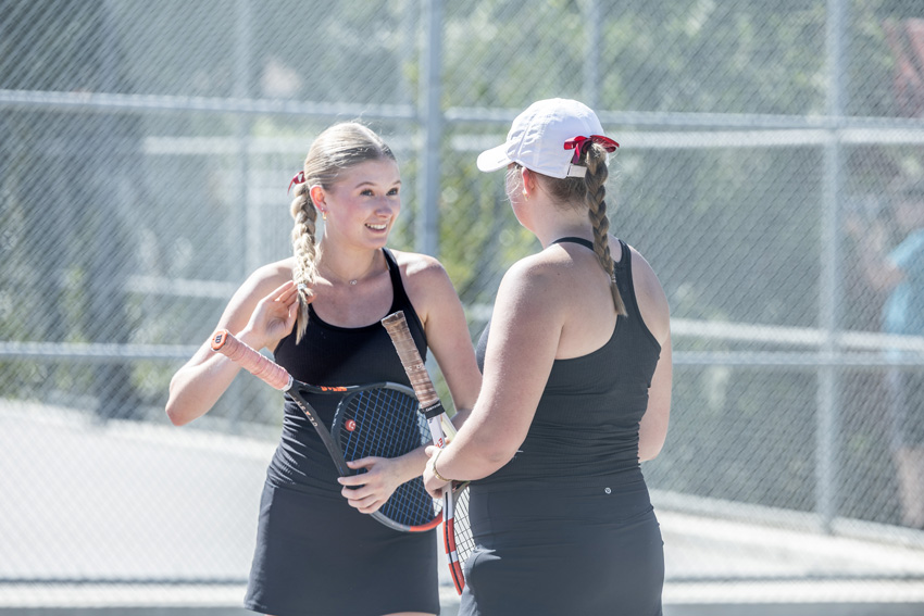 Seniors, Delaney Meyers and Georgia Karlson, talk to each other before a game of doubles. 